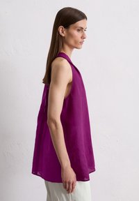 Haut sans manches violet en tissu léger, avec une coupe ample, un encolure ronde et des fentes latérales pour une circulation d'air et un confort optimal.