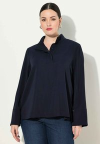 Marineblauw poloshirt met lange mouwen, een kraag met knopen, een ontspannen pasvorm en zijslitsen. Gemaakt van gladde stof met een lichte glans en zonder patronen.
