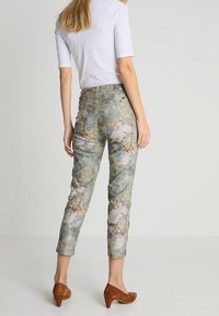 Pantalons fuselés à motif floral en mélange de tissus doux de verts, bleus et roses, avec une taille mi-haute et une coupe à la cheville.