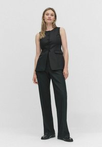 Svart skräddarsydd väst och vida byxor, med knäppt framtill och två sidofickor. Slät tyg med en strukturerad passform.