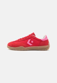 Røde ruskinds sneakers med lyserøde accenter, prydet med et stjernelogo, struktureret sål og snørebåndsdesign. Glat inderside, lavt snit.