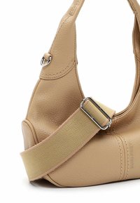 Sac à main en cuir beige avec une forme arrondie, featuring une finition texturée, une large bandoulière en nylon et des accents en métal argenté.
