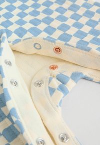 Body din material în carouri albastru deschis și crem, cu închideri cu capse argintii, cupru și albastre. Textură moale, cu guler și margini ale mânecilor în relief.