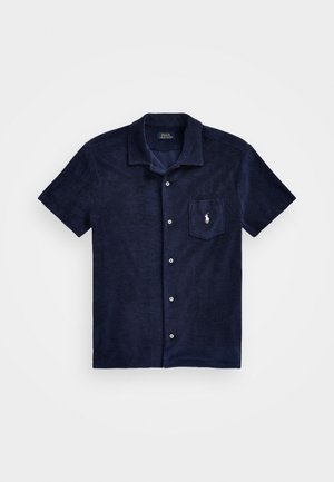 Camisa de manga corta azul marino hecha de tela texturizada, con cierre de botones en la parte delantera, cuello de punta y un bolsillo en el pecho con un logotipo.