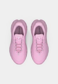 Paire de chaussures de sport Lacoste roses avec texture côtelée, lacets et logo de la marque sur la languette et le côté, vues de dessus sur fond blanc.