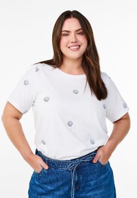 White short-sleeve T-shirt with blue shell embroidery, round neckline, paired with a blue denim skirt featuring a tie belt detail.