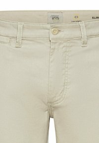 Beige slim-fit bukser lavet af strækstof, med knaplukning og standardlommer. Mærket siger "camel active." Struktureret overflade.