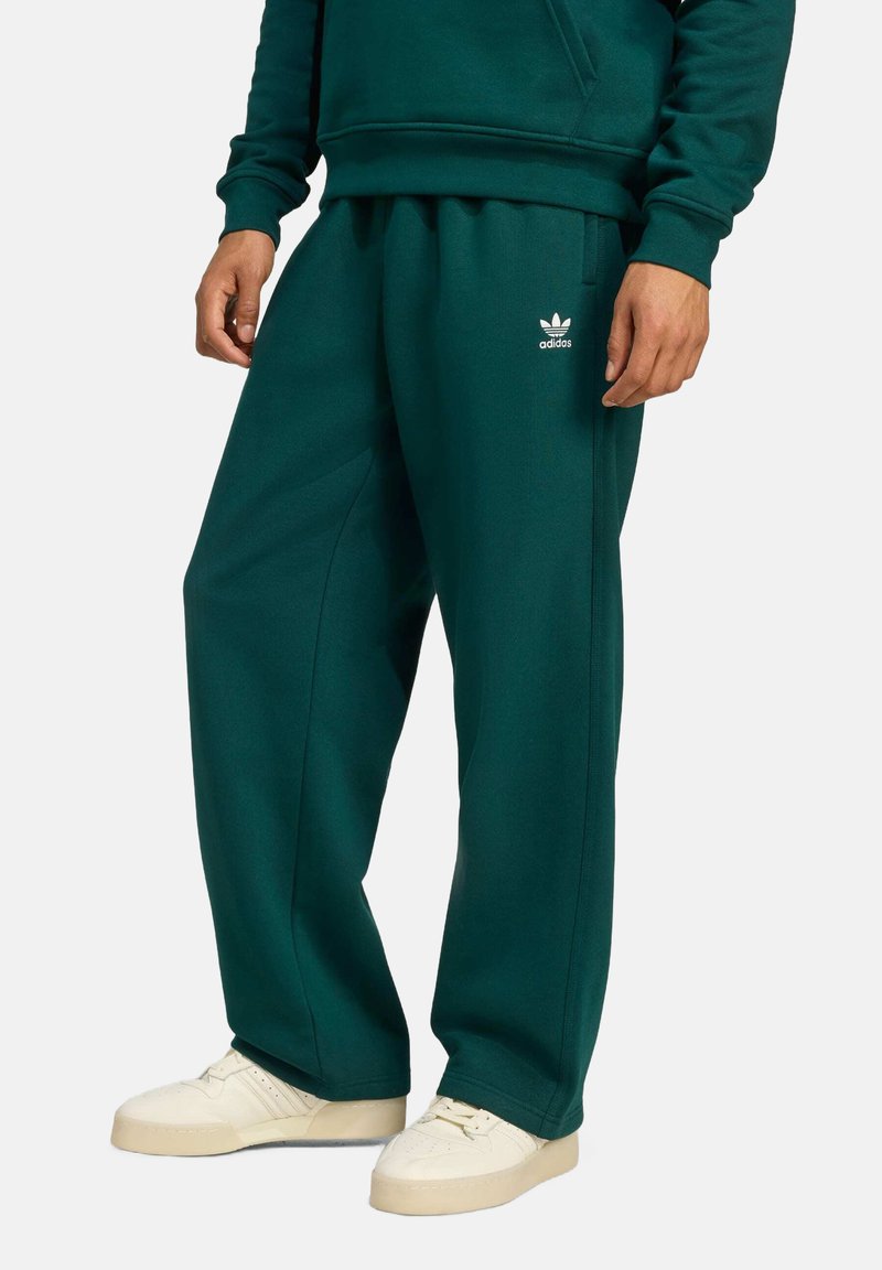 Groene sweatpants van zacht materiaal met een elastische tailleband, zijzakken en een klein wit Adidas-logo op de linkerdij.