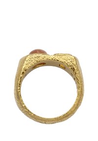 Guldtexturerad ring med en rund, slät rosa sten på toppen. Ringen har en ojämn, organisk yta och en bred design.