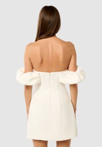 Vestido mini blanco sin hombros con mangas abullonadas, corpiño ajustado y cremallera en la parte posterior. Tejido suave con una silueta estructurada.