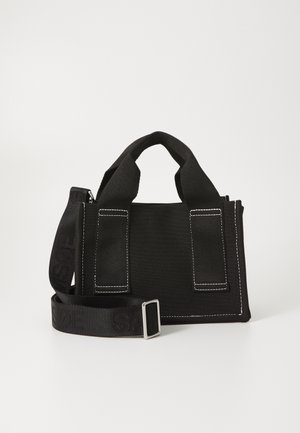 Petit sac à main en tissu noir avec doubles anses supérieures et bandoulière réglable, présentant un texte discrètement embossé.