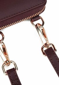 Burgundy faux leather wallet with a gold-tone zipper and hardware, featuring a smooth texture and detachable strap with snap hooks.