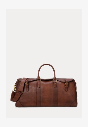 Καφέ δερμάτινη τσάντα duffel με διπλές επάνω λαβές, ρυθμιζόμενο λουράκι ώμου και χρυσαφί απολήξεις κουμπωμάτων μπροστά και στα πλευρά.