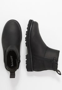 Botas de tornozelo em pele preta com um acabamento texturizado, biqueira redonda, fecho lateral com zip e sola de borracha com ranhuras para maior tracção.