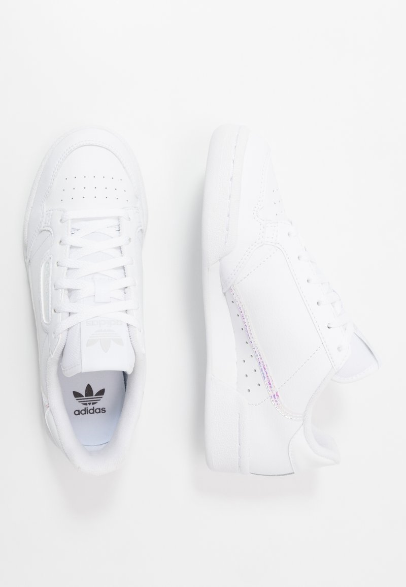 Baskets blanches avec une tige en cuir lisse, des détails perforés et des lacets. Présente un subtil accent irisé sur le panneau latéral.