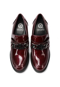 Mocassini in pelle brillante bordeaux con un accento in catena nera. Punta arrotondata e suola nera piatta. Interno con soletta stampata con logo.