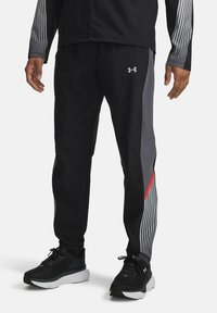 Black athletic pants with grey and red accents, featuring sleek design and tapered fit. Made of lightweight material with a smooth texture.