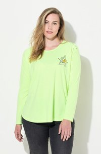 Langärmliges, neongrünes Shirt mit einem Sternmotiv und orangenen Akzenten, Rundhalsausschnitt und seitlichen Schlitzen. Weicher, leichter Stoff.