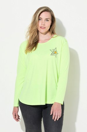 Langärmliges, neongrünes Shirt mit einem Sternmotiv und orangenen Akzenten, Rundhalsausschnitt und seitlichen Schlitzen. Weicher, leichter Stoff.