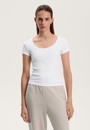 Tricou alb cu mânecă scurtă, din tricot cu decolteu rotund, design ajustat și textură netedă, purtat cu pantaloni de lounge din bumbac gri deschis.