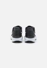 Zapatillas deportivas negras con parte superior de malla texturizada, acentos blancos y una suela acolchada. Presenta un logotipo de estrella en el talón.