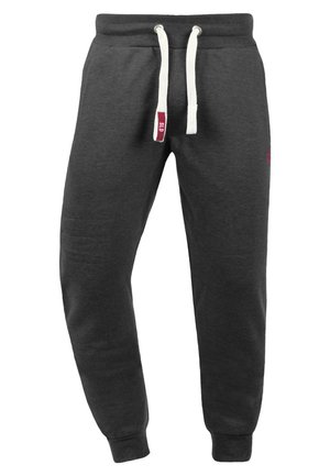 Pantalons de survêtement gris foncé en tissu doux, avec une taille élastique à cordon blanc et des poignets côtelés aux chevilles. Petit détail de logo rouge.