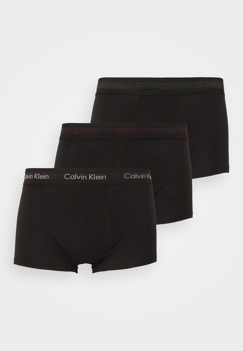 Trei perechi de boxeri negri. Fiecare are un tiv moale cu logo-ul "Calvin Klein" în culori contrastante. Materialul pare neted și elastic.
