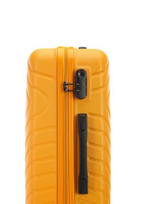 Valise rigide de couleur orange vif avec surface texturée, double zip, poignée noire et mécanisme de verrouillage sur le côté.