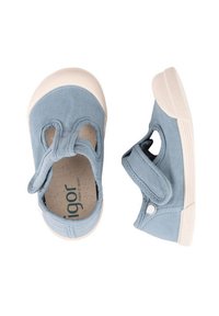 Zapatillas de lona azul claro con puntera redonda, banda elástica y cierre de velcro. Suelas de goma color crema y una superficie superior texturizada.