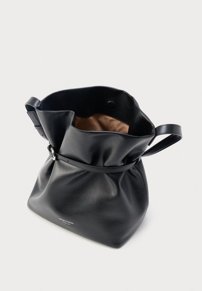 Μαύρη δερμάτινη τσάντα ώμου με λεπτό λουρί, ασημένια πόρπη και εσωτερική επένδυση ανοιχτού καφέ χρώματος, τοποθετημένη πάνω σε απλό φωτεινό φόντο.