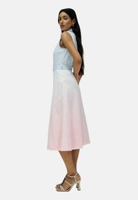Vestido sin mangas de color azul claro con cintura ceñida, que transiciona a una falda rosa. Presenta costuras en panel y un diseño fluido. Estilizado con tacones de tiras beige.