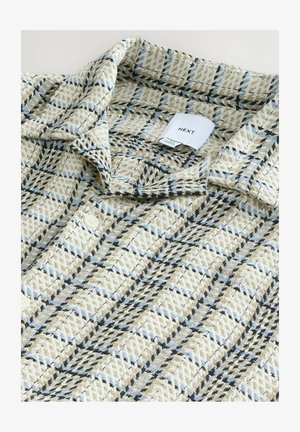 Beež punutud särk, millel on sinise ja musta ruuduline muster. Nööpidega kinnitamine, krae ja sisseõmmeldud silt, millel on kirjas "NEXT."