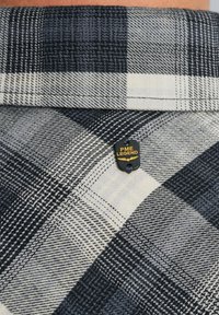 Flanellen overhemd met een zwart-wit geruit patroon, voorzien van een zwart label met "PME LEGEND" in het geel. Gestructureerde stof en gestructureerde kraag.