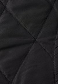 Sort quilted stof med et diamantmønster, der har en glat tekstur og synlige syninger. Letvægts og mat finish.