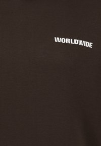 Braunes T-Shirt mit kurzen Ärmeln aus weichem Material, das das Wort "WORLDWIDE" in fett gedrucktem Weiß auf der linken Brustseite trägt.