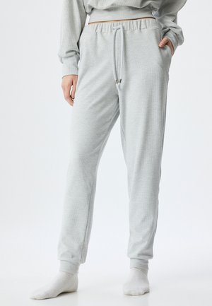Grijze geribbelde joggingbroek met een elastische tailleband, trekkoord en zijzakken. Zachte textuur; taps toelopende pasvorm bij de enkels.