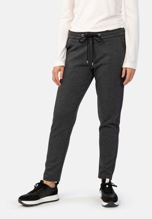 Graue Jogginghose mit strukturiertem Finish, elastischem Bund, verstellbarem Kordelzug und Seitentaschen, kombiniert mit schwarzen Sneakers.