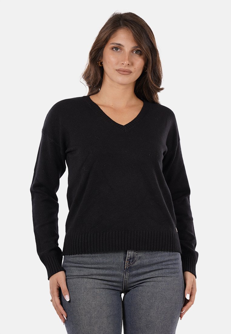 Maglione nero a maglia con scollo a V, orlo a coste e maniche lunghe, realizzato in tessuto morbido, abbinato a jeans di denim.