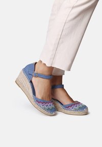 Blå tygklädda kilklackade espadrilles med flerfärgad zigzag-broderi, ankelsnodd och sula i jute. Avslappnad design som passar för varmt väder.