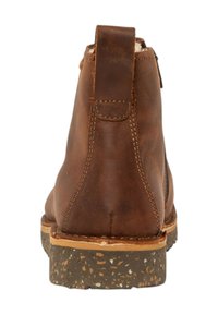 Bota de tobillo de cuero marrón con superficie texturizada, talón trasero elevado, costuras en contraste y suela de goma resistente y moteada.