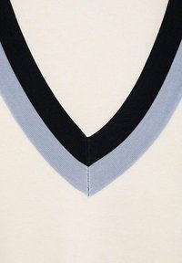 T-shirt à col en V avec un corps beige et un col côtelé noir et bleu clair. Texture lisse, coutures finement réalisées.