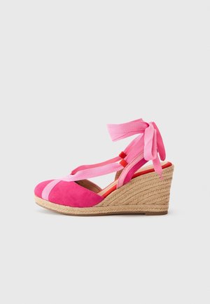 Pink kileformet espadrillesko med ankelbånd og fletet jutesål på en ensartet lys baggrund.