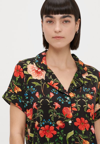 Camisa de pijama preta com padrão floral, featuring mangas curtas, colarinho e fecho com botões. O design inclui flores vermelhas, cor-de-rosa e azuis.