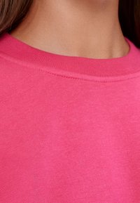 Fuchsia ronde hals t-shirt gemaakt van soepele katoen; beschikt over een ribbelboord en nette stiksels langs de randen.