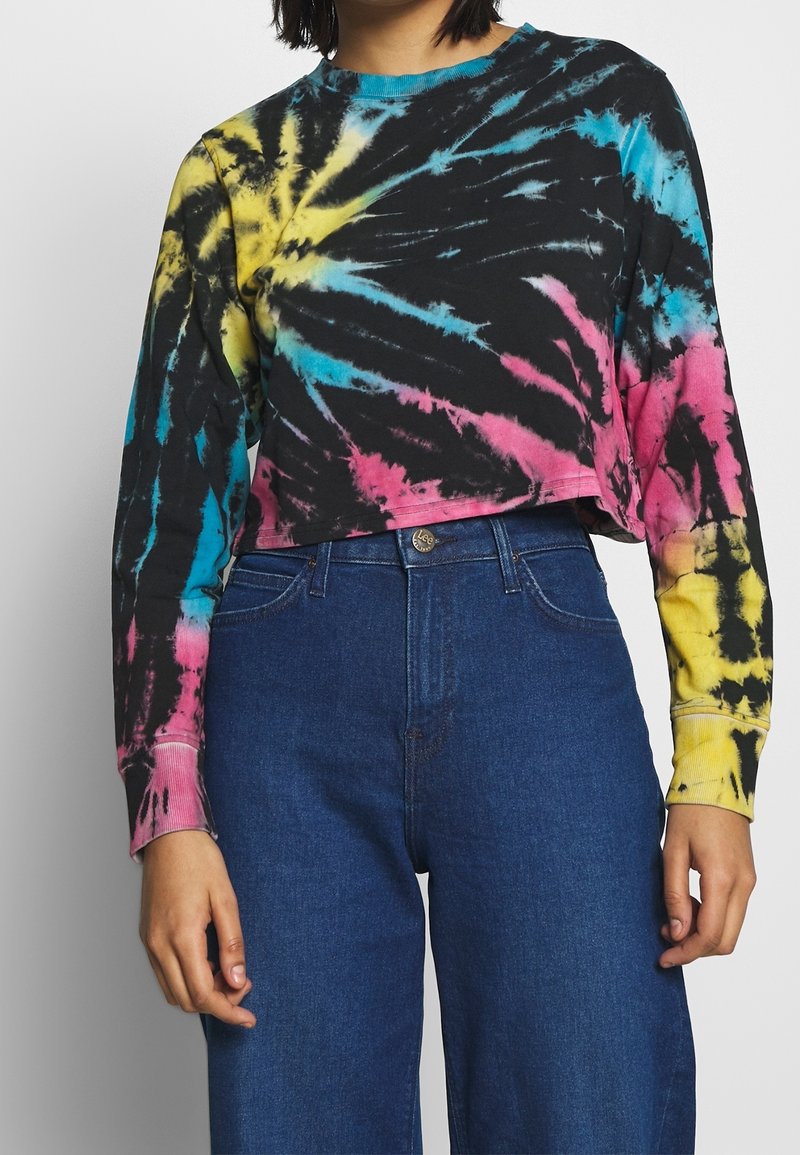 Cropped long-sleeve shirt in black with tie-dye patterns in pink, yellow, and blue. Cotton material with ribbed cuffs and neckline.