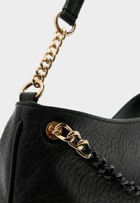 Sac à main en cuir noir avec une finition texturée, doté d'une anse en chaîne dorée et d'accents noirs. Comprend un détail en métal pour la sécurisation.