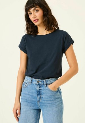 Navy blue short-sleeve t-shirt with rolled cuffs, paired with high-waisted, light blue denim jeans. Smooth texture, casual fit.