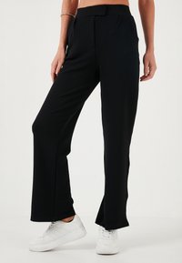 Zwarte flared broek gemaakt van een gladde stof, met een platte voorkant met plooien, een middelhoge tailleband en afgewerkt met een rechte zoom.