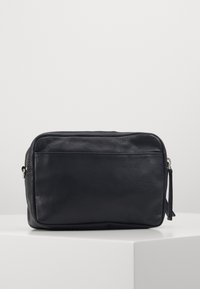 Sort lædertaske med en rektangulær form, lynlåslukning, struktureret overflade og en sideløkke. Minimalistisk design uden synlige mønstre.