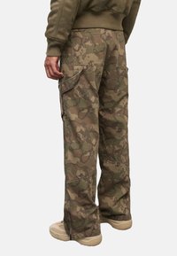 Cargo-Hosen in einem Tarnmuster mit Grüntönen und Brauntönen. Verfügt über Taschen an den Seiten und strapazierfähigem Stoff mit lockerer Passform.